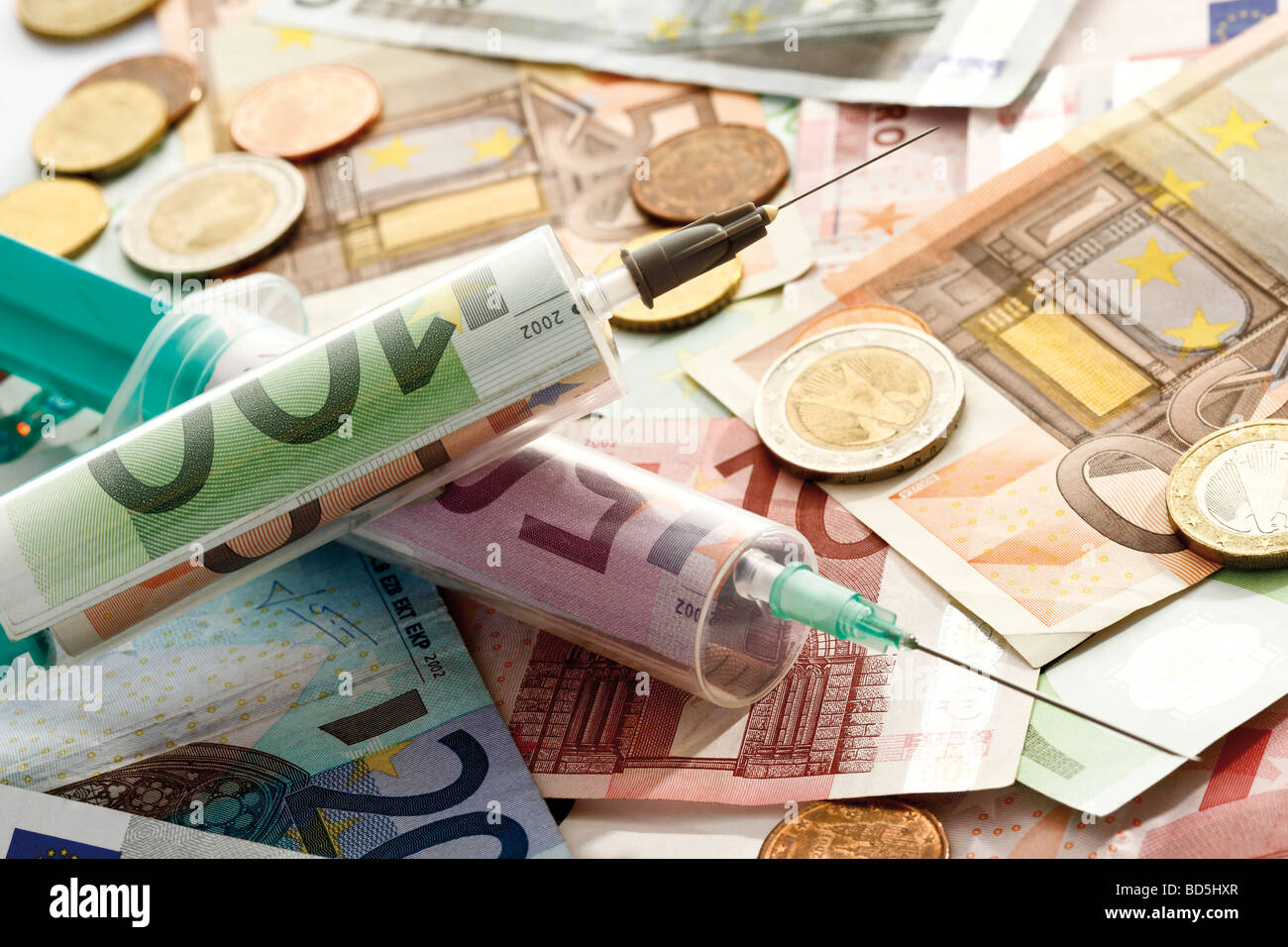 Los billetes de banco, monedas, jeringas, imagen simbólica para inyectar dinero Foto de stock