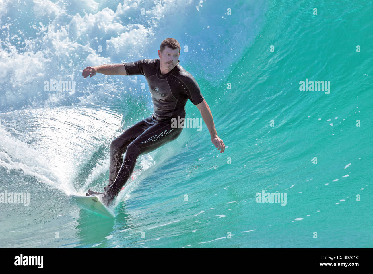 Surfer capta una onda para un paseo a la orilla tarde Foto de stock