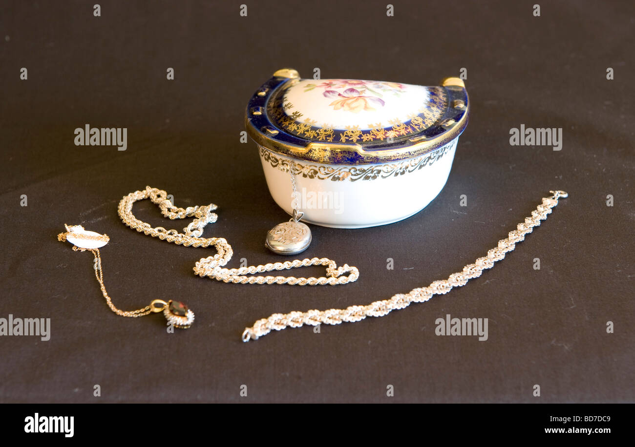 Porcelana olla abalorio con forma de herradura, rodeado por diversas joyas de plata medallón Collar y brazalete Foto de stock