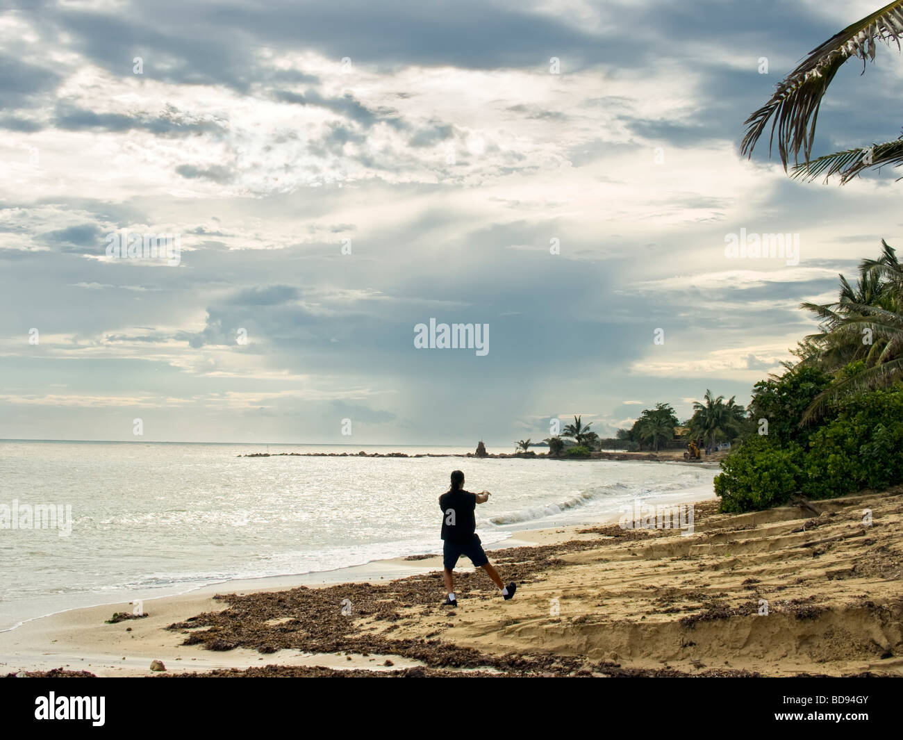 Un hombre solitario de prácticas de tai chi en la playa después de una tormenta tropical Foto de stock