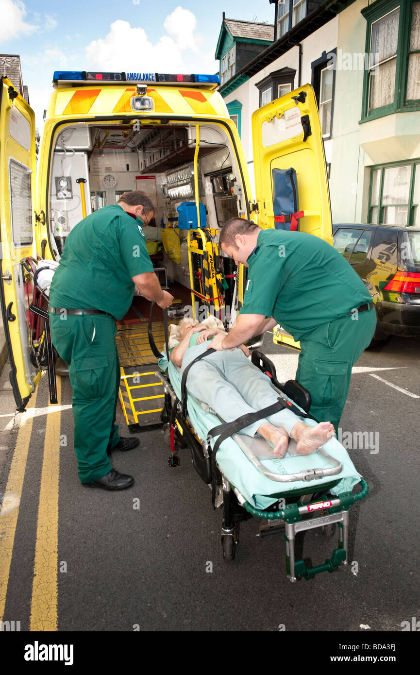 Los paramédicos respondieron a una llamada 999 poniendo anciana que ha caído en casa en una camilla y llevarla al hospital Foto de stock