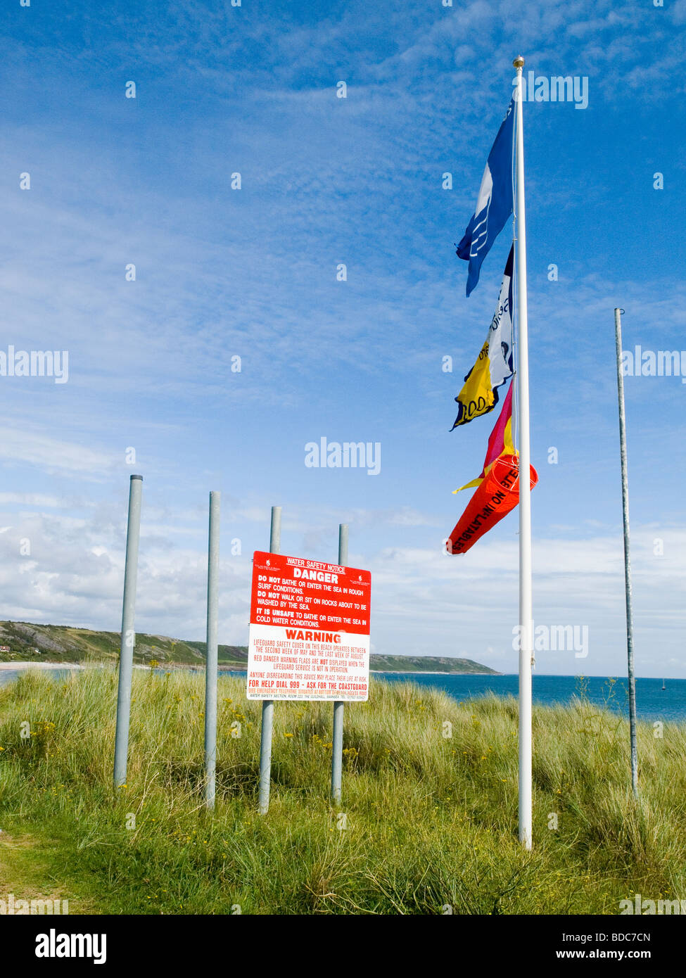 Un aviso de advertencia y banderas ondeando en la playa en Port Eynon, Península de Gower Swansea Wales UK Foto de stock