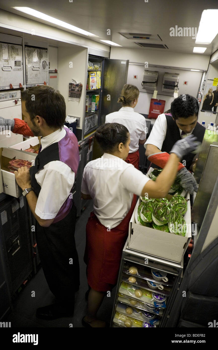 Los miembros de la tripulación de cabina se preparan para servir las comidas en la cocina de un Virgin Atlantic la aeronave durante el vuelo de Londres a Mumbai. Foto de stock