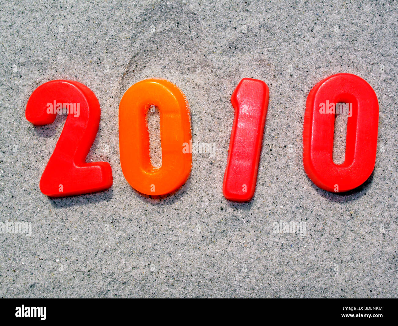 Año 2010 en números rojos y naranjas contra un fondo de arena Foto de stock