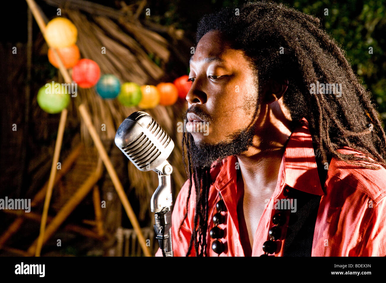 Joven hombre jamaiquino con dreadlocks cantando en isla tropical Foto de stock
