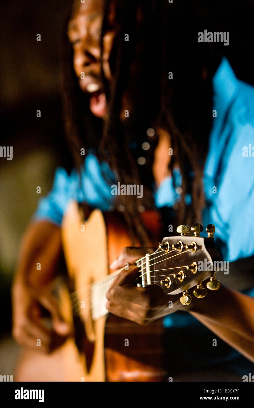 Joven hombre jamaiquino con dreadlocks tocando la guitarra en una isla tropical Foto de stock