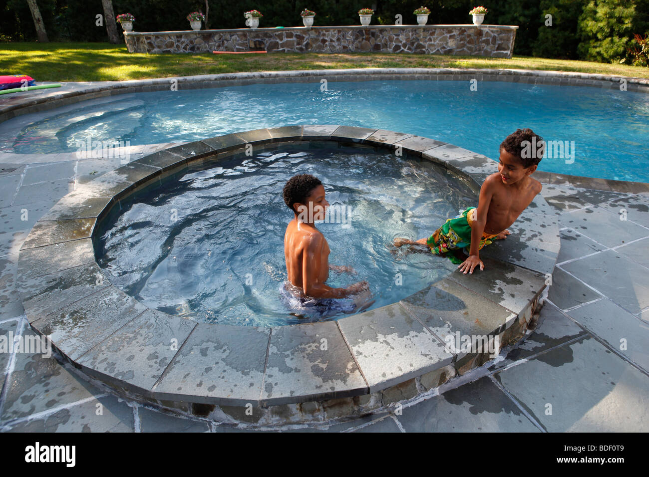 Dos niños, de 8 y 10 años de edad, juega en un patio con piscina, Sag Harbor, Nueva York Foto de stock