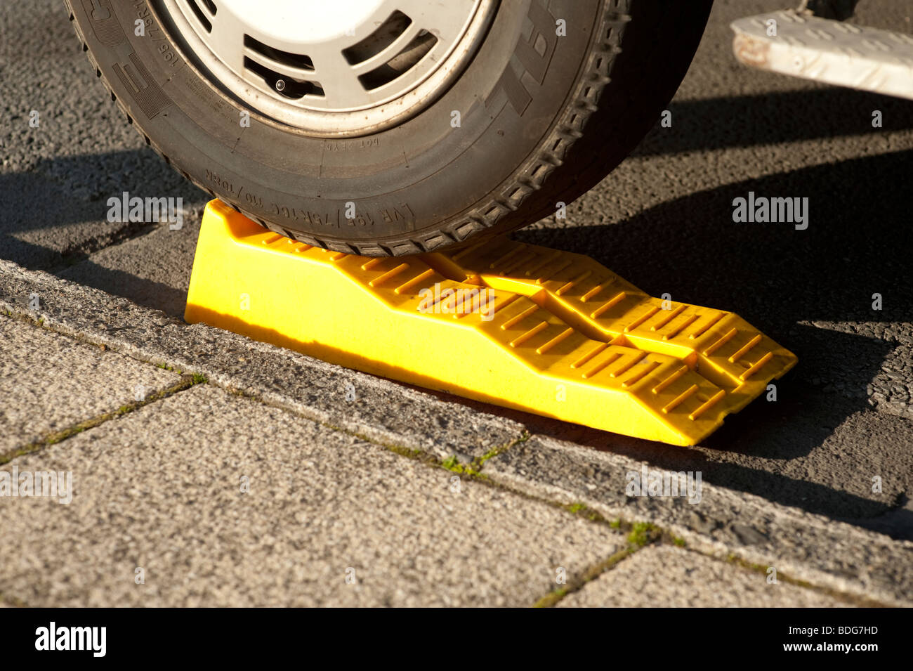 Paso de plástico amarillo calzos de cuña colocada bajo el volante de una  autocaravana para nivelar el vehículo cuando está estacionado en el camino  de la noche a la mañana Fotografía de