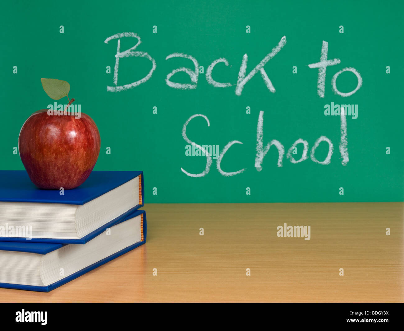 Back to school escrito en una pizarra con una manzana más libros. Foto de stock