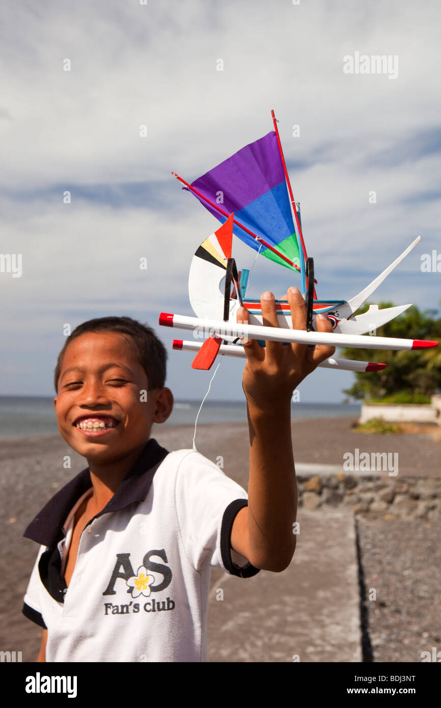 Indonesia, Bali, Amed, niño sosteniendo recuerdos hechos a mano pintados  coloridamente outrigger barco pesquero modelo Fotografía de stock - Alamy