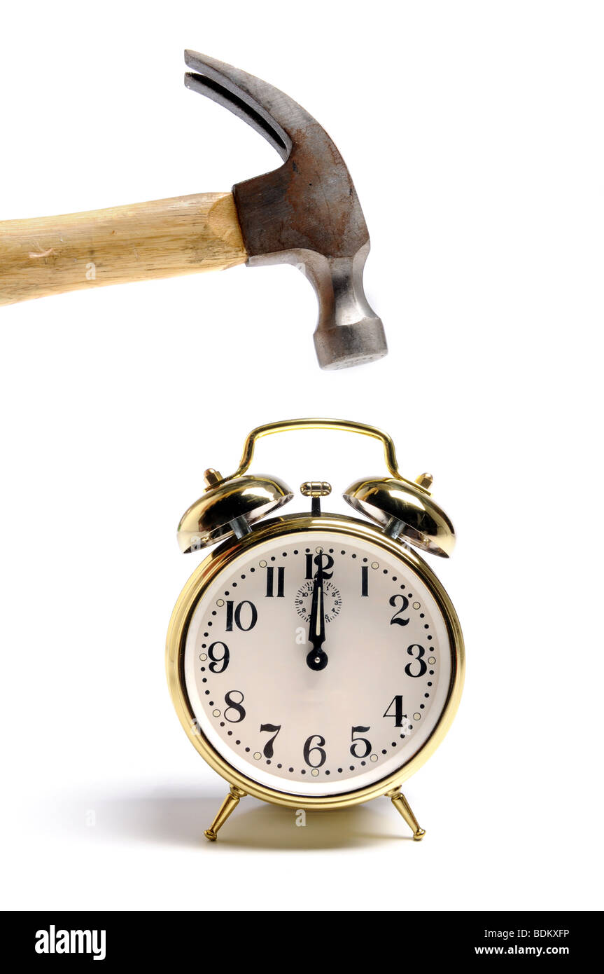 Reloj con alarma y un martillo sobre un fondo blanco. Foto de stock