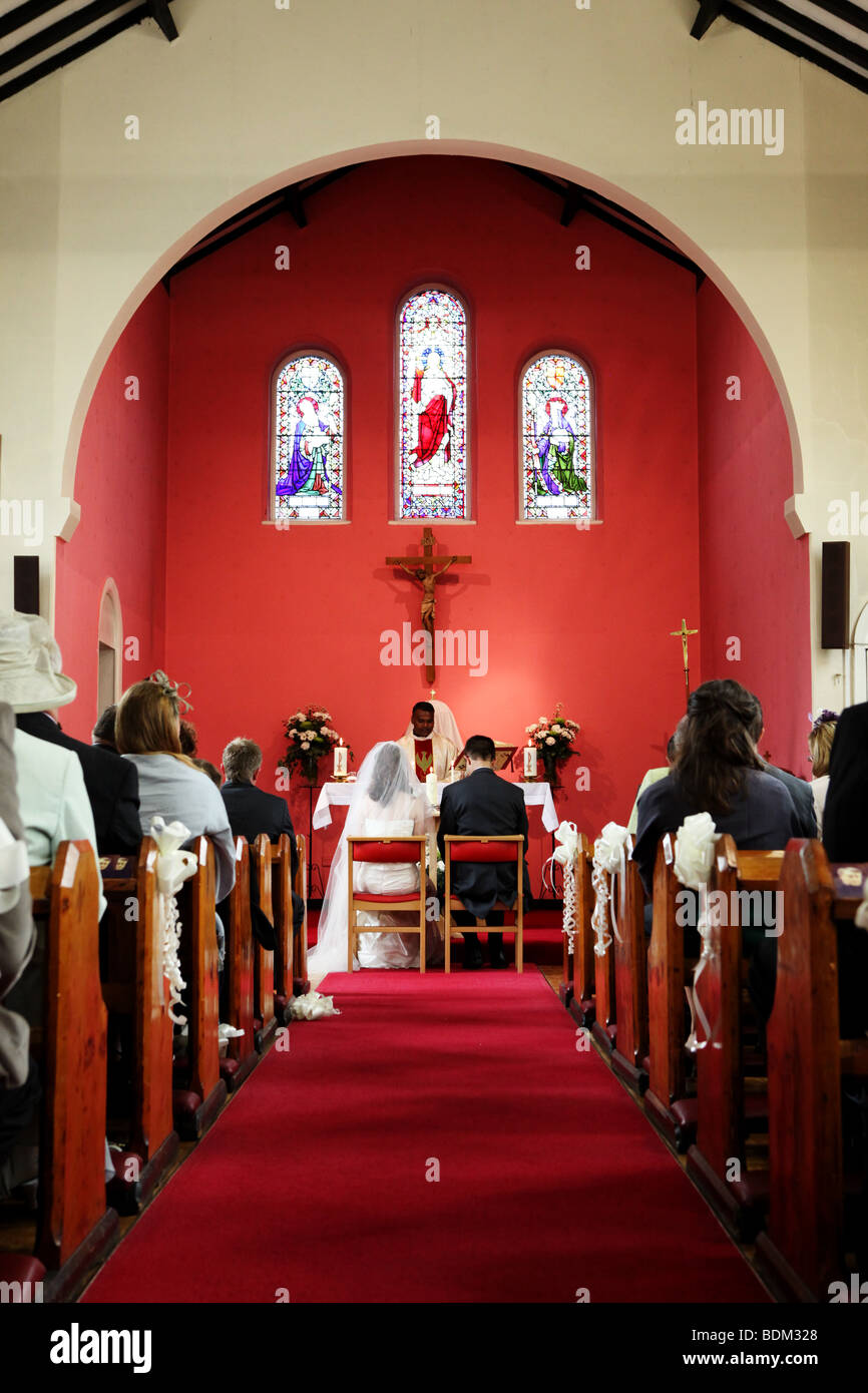 Iglesia isle con alfombra roja y la novia y el novio sentado en la ceremonia de boda en el altar del reportaje fotográfico de boda estilo image UK Foto de stock