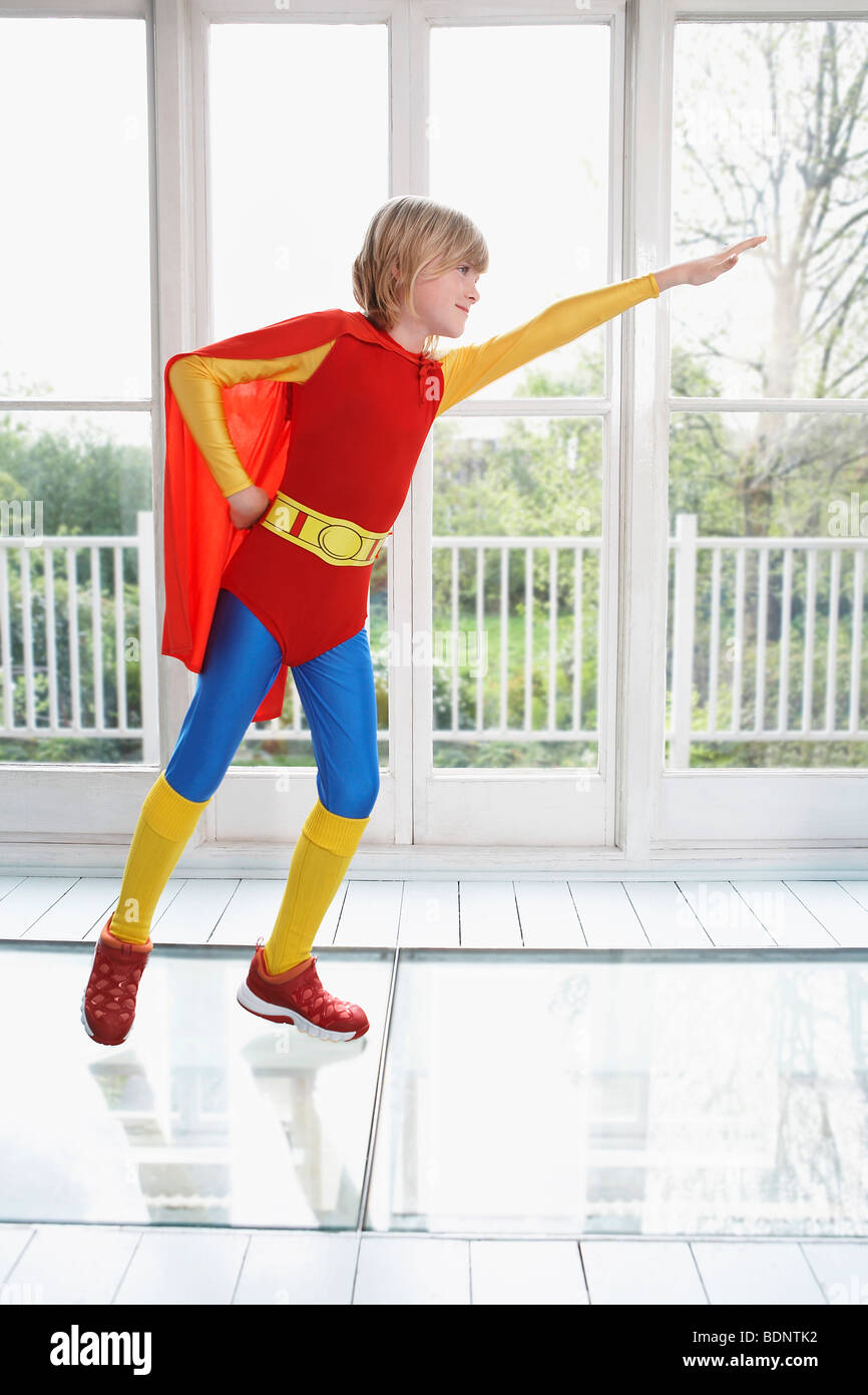 Joven (7-9) vistiendo trajes de superhéroes, con el brazo extendido, vista lateral Foto de stock
