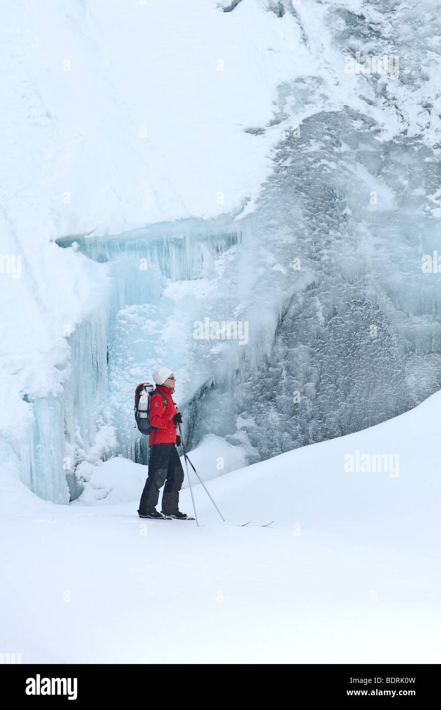 Esquiador hembra delante de una cascada congelada en el parque nacional padjelanta, la Laponia sueca Foto de stock