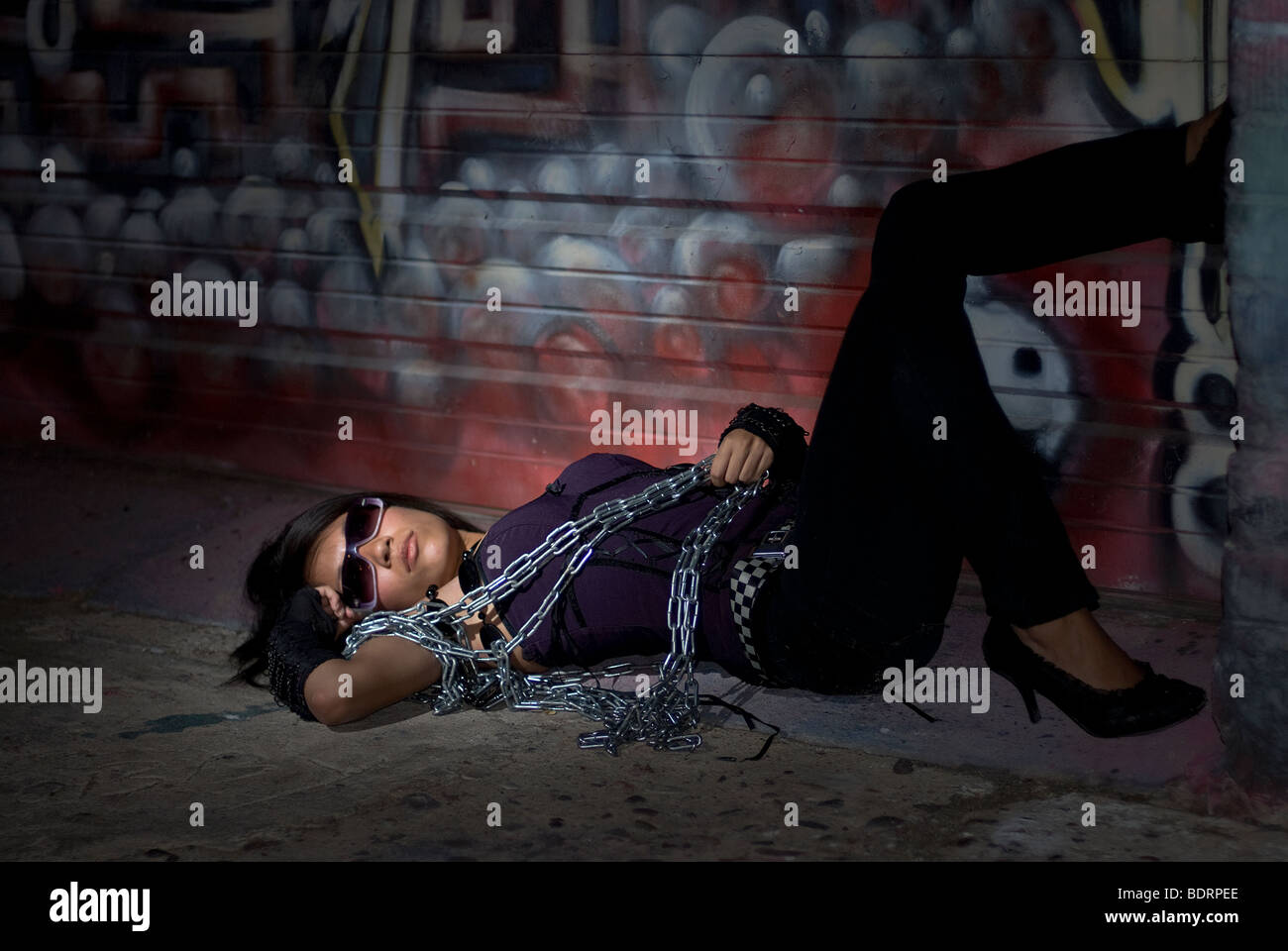 Un joven hispano/Medio Oriente mujer representa en una ubicación urbana en la noche. Foto de stock