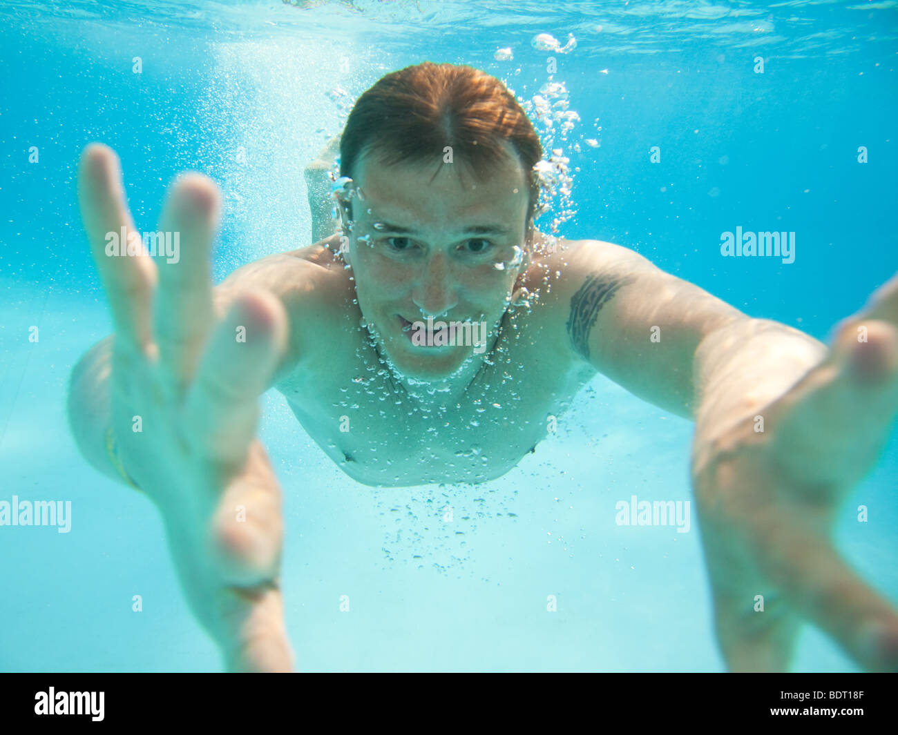Hombre nadando bajo el agua en la piscina Foto de stock