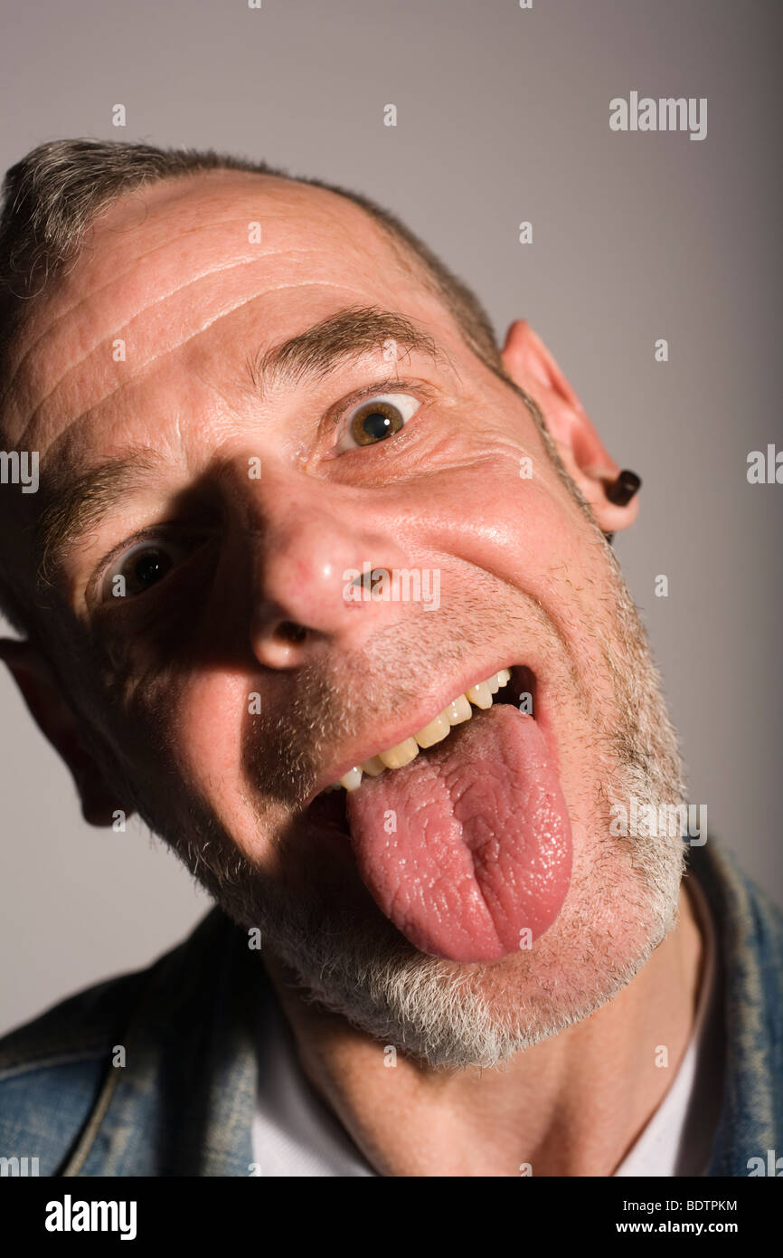 El hombre con aspecto de balancín punk introduciendo su lengua. Foto de stock