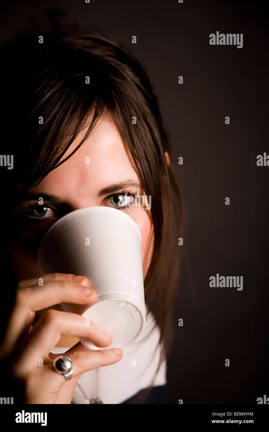 Hermosa joven "ocultar" detrás de una taza de poliestireno. Foto de stock