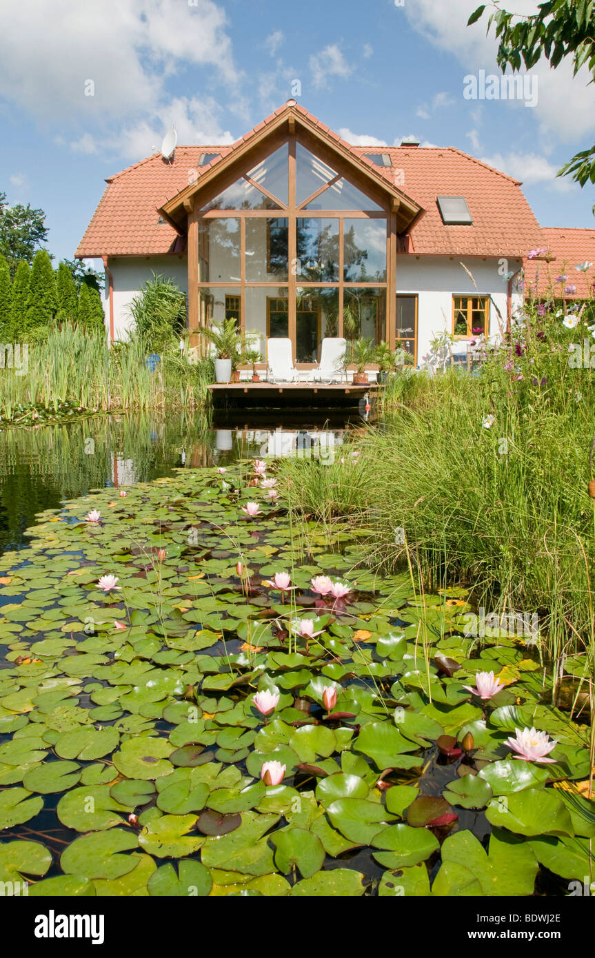 Jardín con estanque de nenúfares, en frente de la casa con jardín de  invierno, en verano Fotografía de stock - Alamy