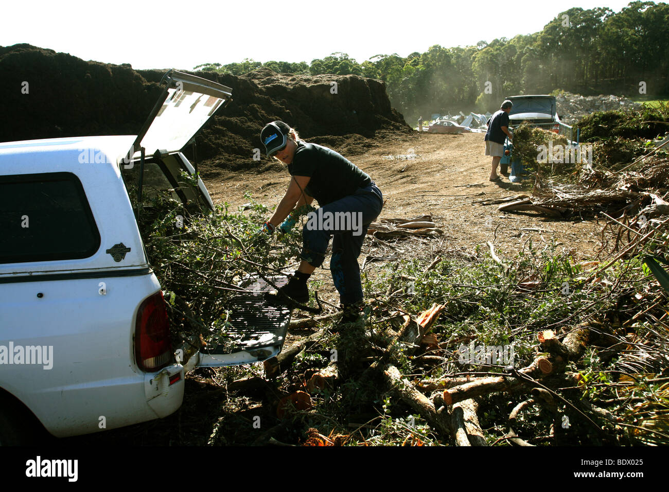 Una mujer recicla residuos verdes del jardín en un basurero donde se convierte en el abono. Foto de stock