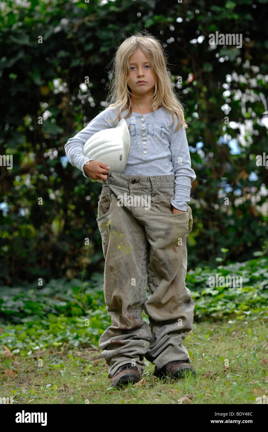 Niña de 7 años vestida con ropa de trabajo con un casco Fotografía de stock  - Alamy