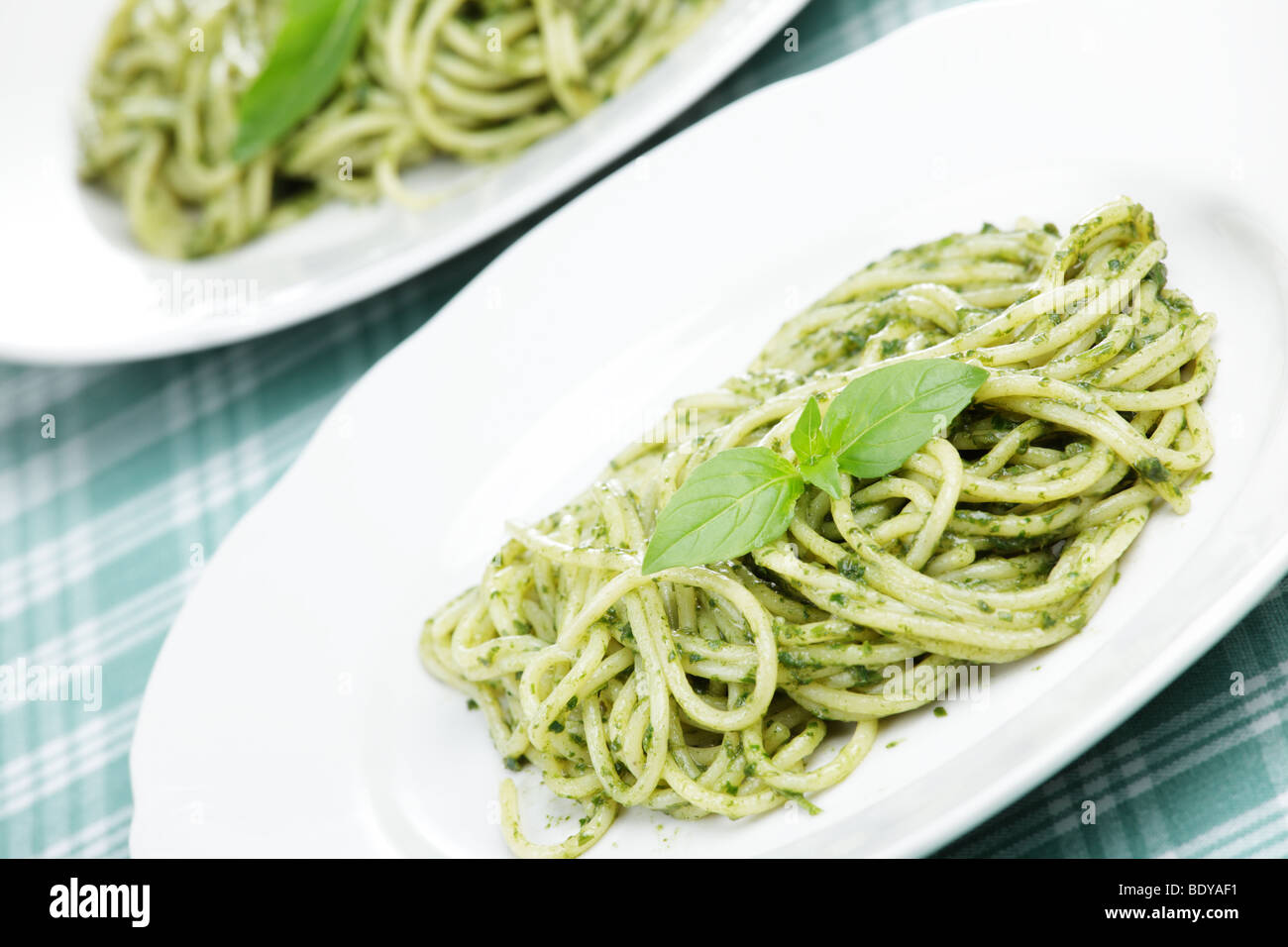 Espaguetis con salsa pesto y hojas de albahaca Foto de stock