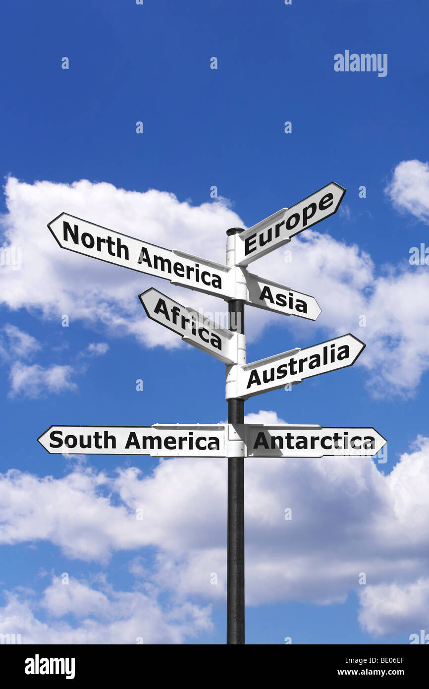 Cartel con flechas apuntando a los siete continentes del mundo contra un azul cielo nublado. Foto de stock