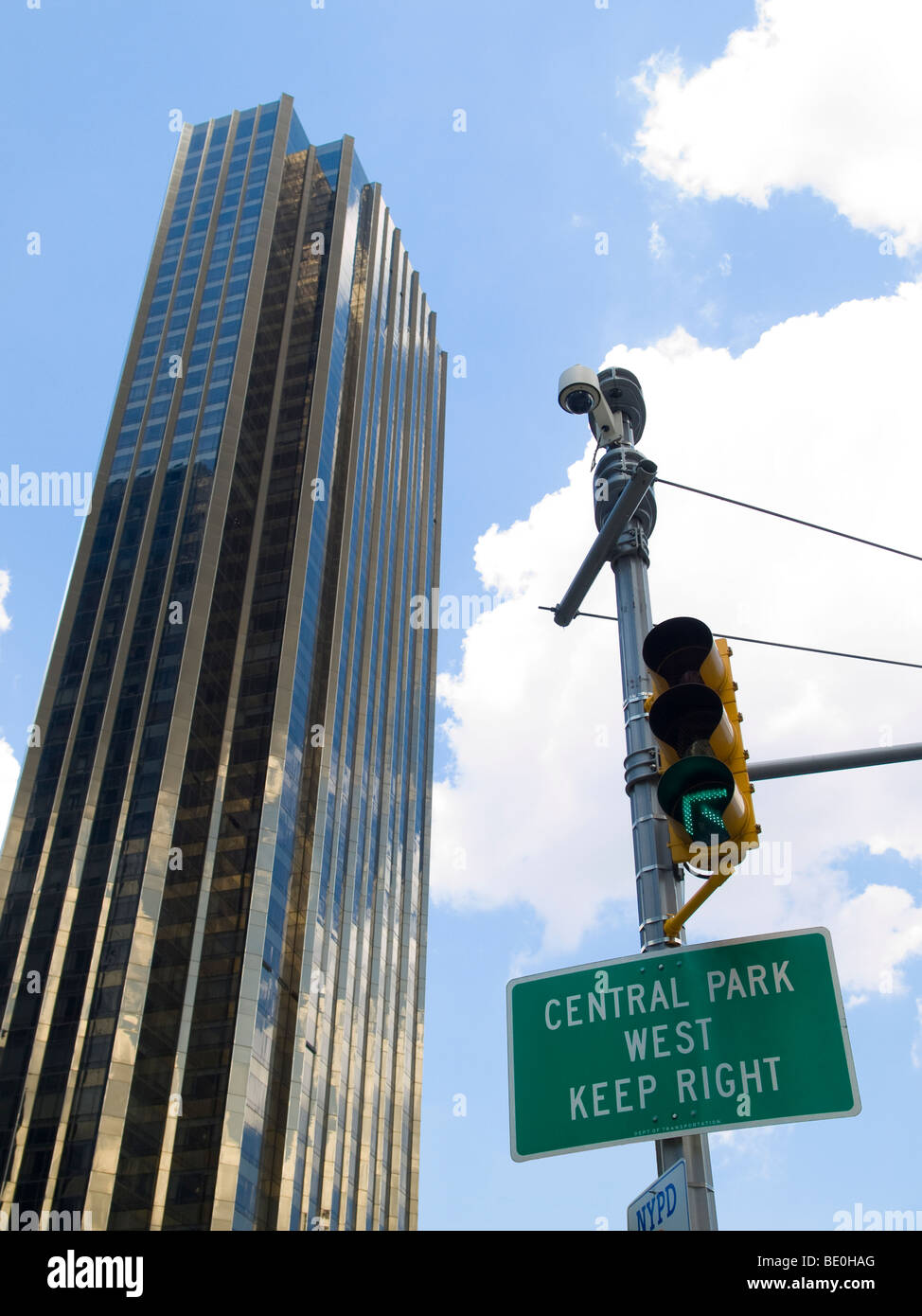 Central Park West canta colgado en un semáforo al lado de un rascacielos en un nublado cielo azul de fondo. Foto de stock