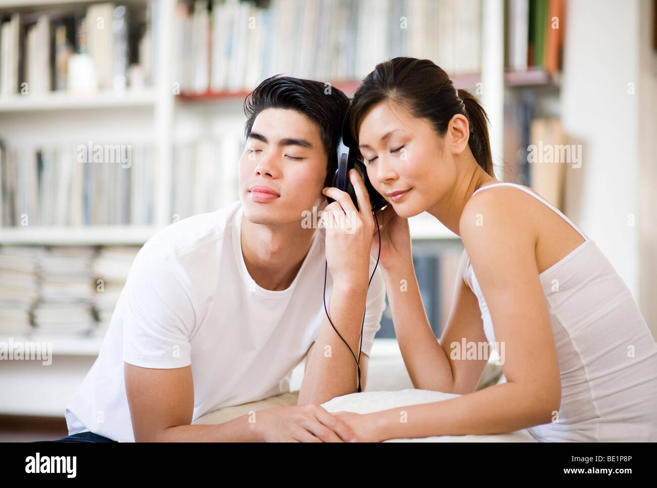 Pareja asiática escuchando música junto con auriculares Foto de stock