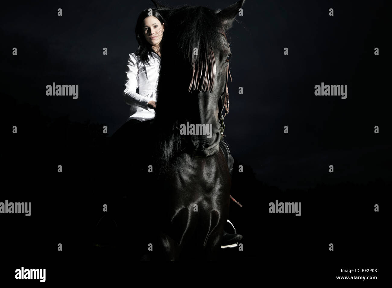 Mujer joven cabalgando sobre su caballo marrón oscuro Foto de stock