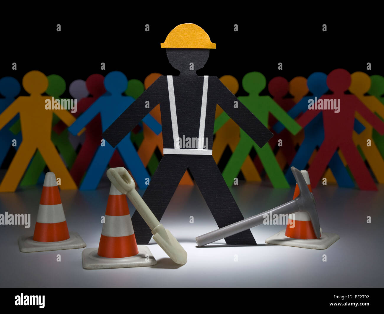 El papel de un trabajador de la construcción se encuentra en el centro de atención con sus herramientas y conos. Foto de stock