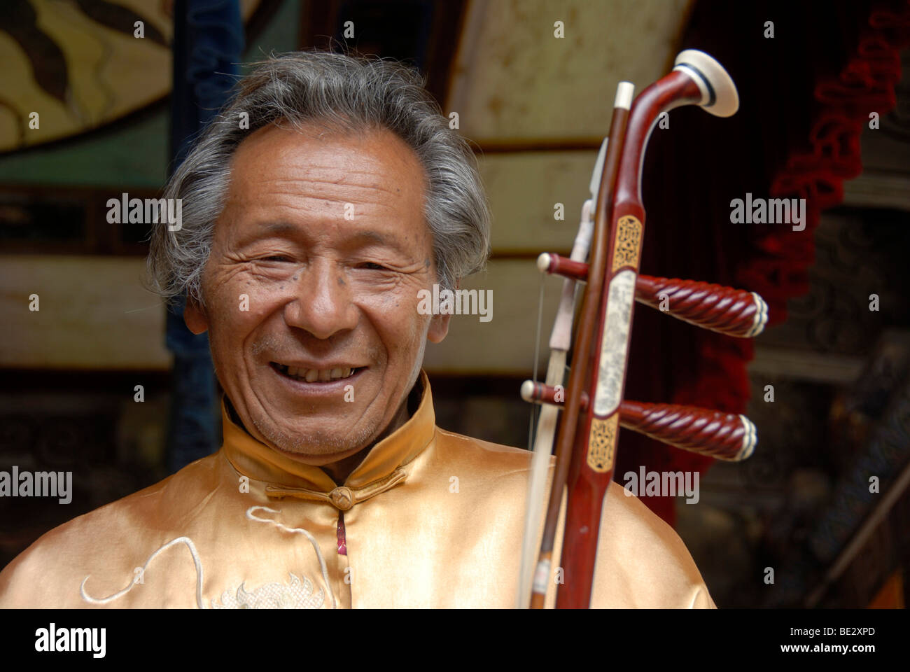 Retrato, músico, Nakhi Naxi sonriente, el hombre con el instrumento de cuerda, Lijiang, Sitio del Patrimonio Mundial de la UNESCO, en la provincia de Yunnan, Peopl Foto de stock