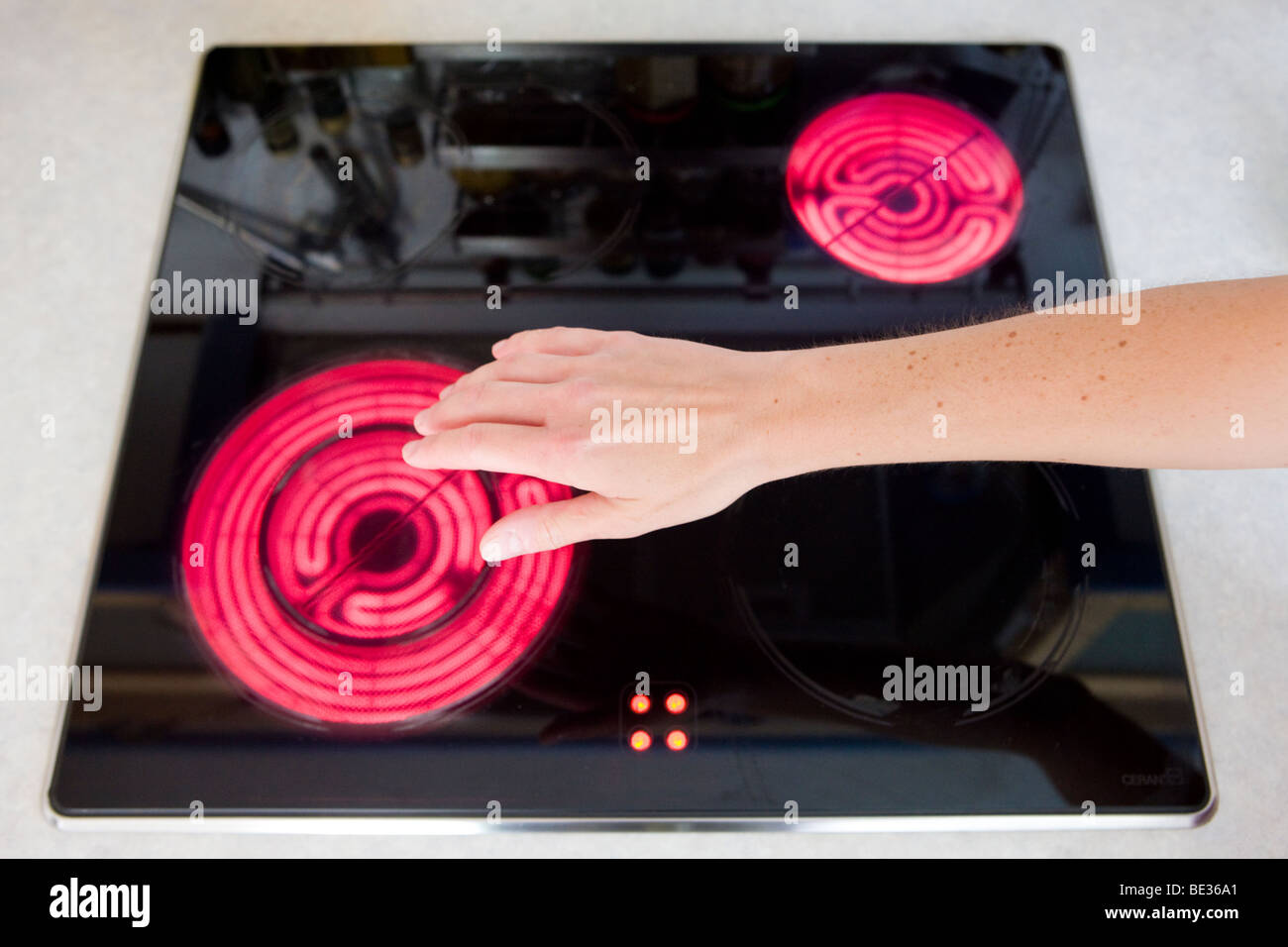Accidentes domésticos, niña tocando la placa calefactora radiante Foto de stock