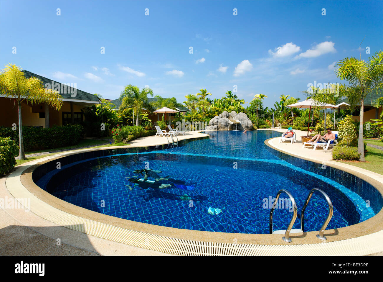 Formación de buceadores, turistas en tumbonas en la piscina, bungalows con sus verdes alrededores, Palm Garden Resort, Khao Lak, Phuket, Thail Foto de stock