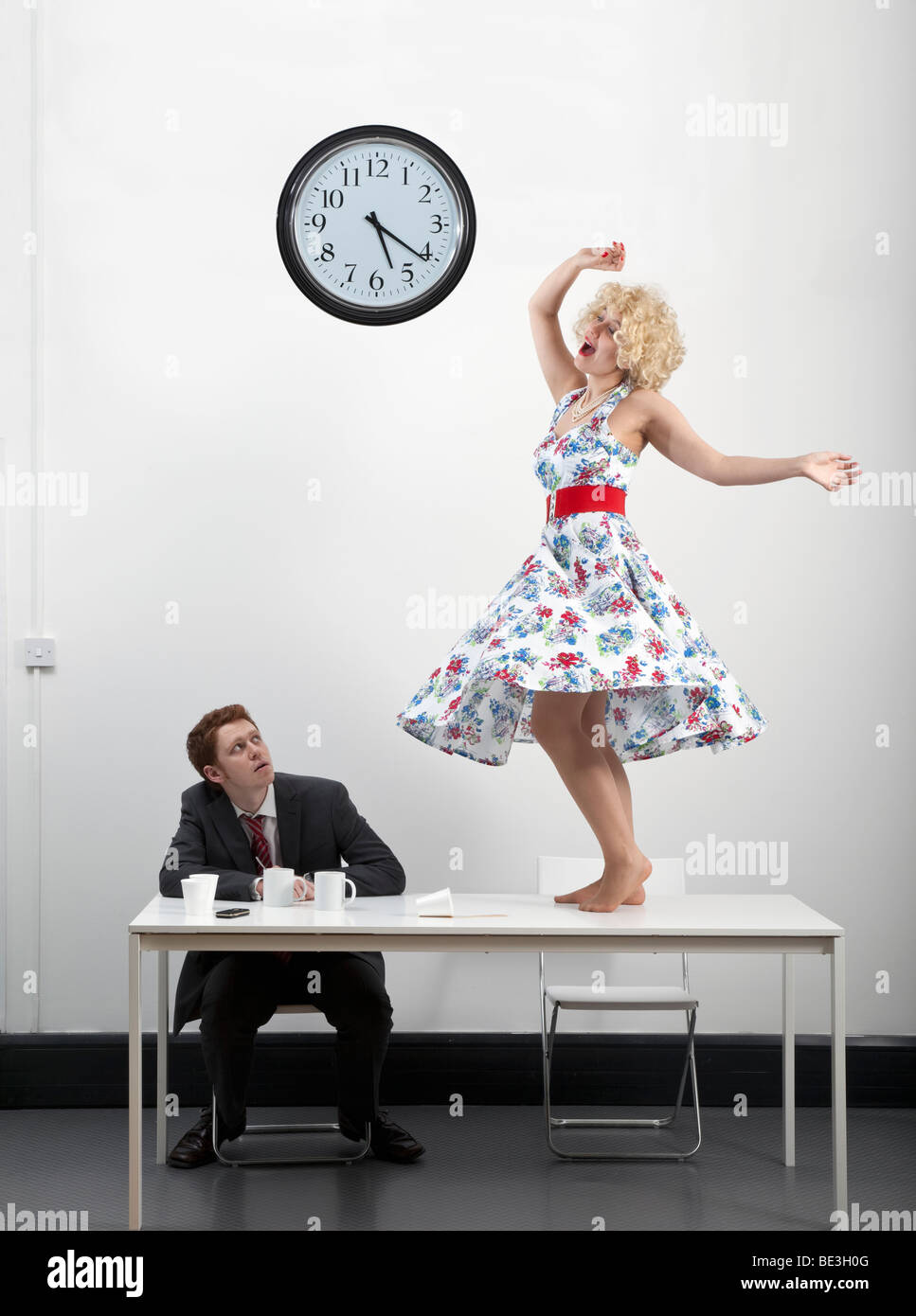 Mujer baila sobre la mesa durante la pausa para el café Foto de stock