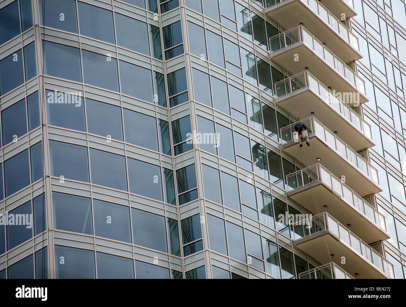 Obrero contra un balcón en lo alto de un rascacielos Foto de stock