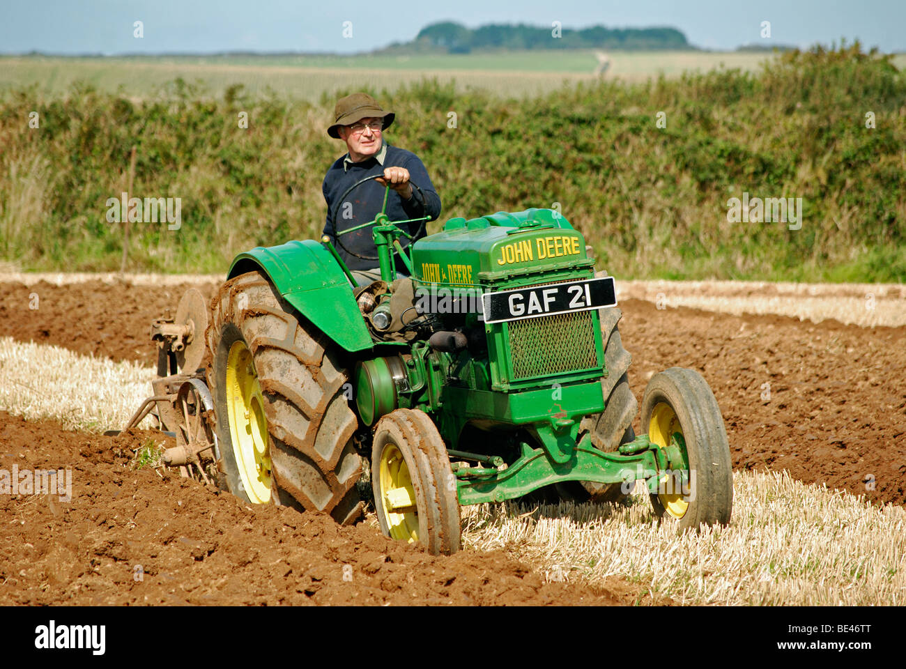 Un agricultor arando un campo con un tractor viejo,Cornwall, UK Foto de stock