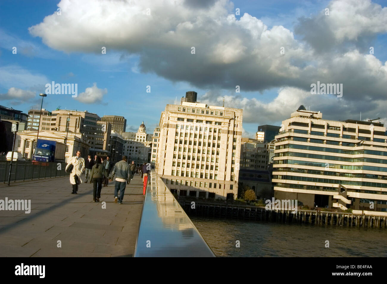 Personas que cruzan el Puente de Londres y un buen día con algunas nubes, en dirección a la ciudad de Londres. Foto de stock