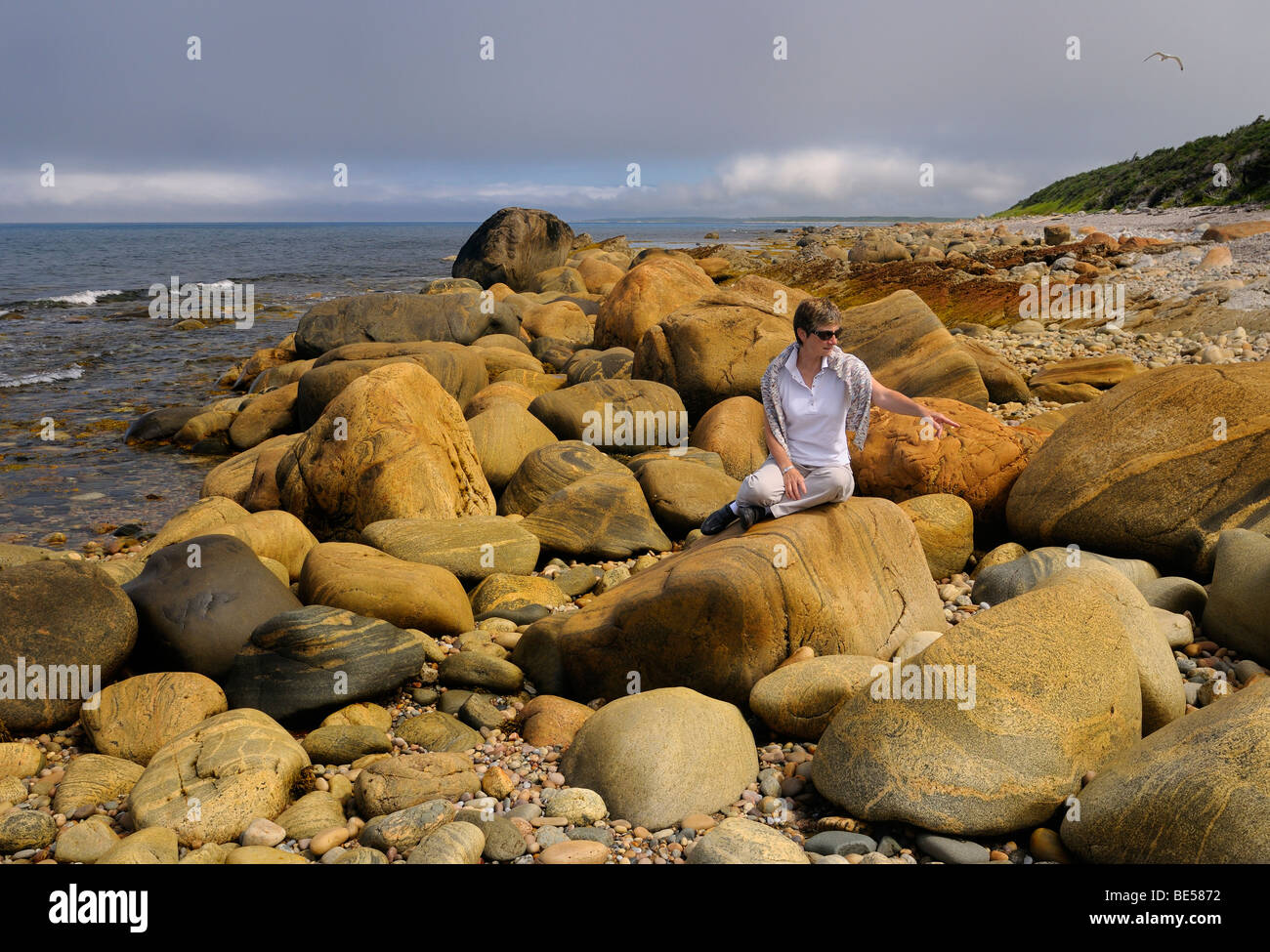 Turista apuntando a color óxido rocas en la orilla de Martins punto golfo del San Lorenzo, Océano Atlántico Terranova Canadá Foto de stock