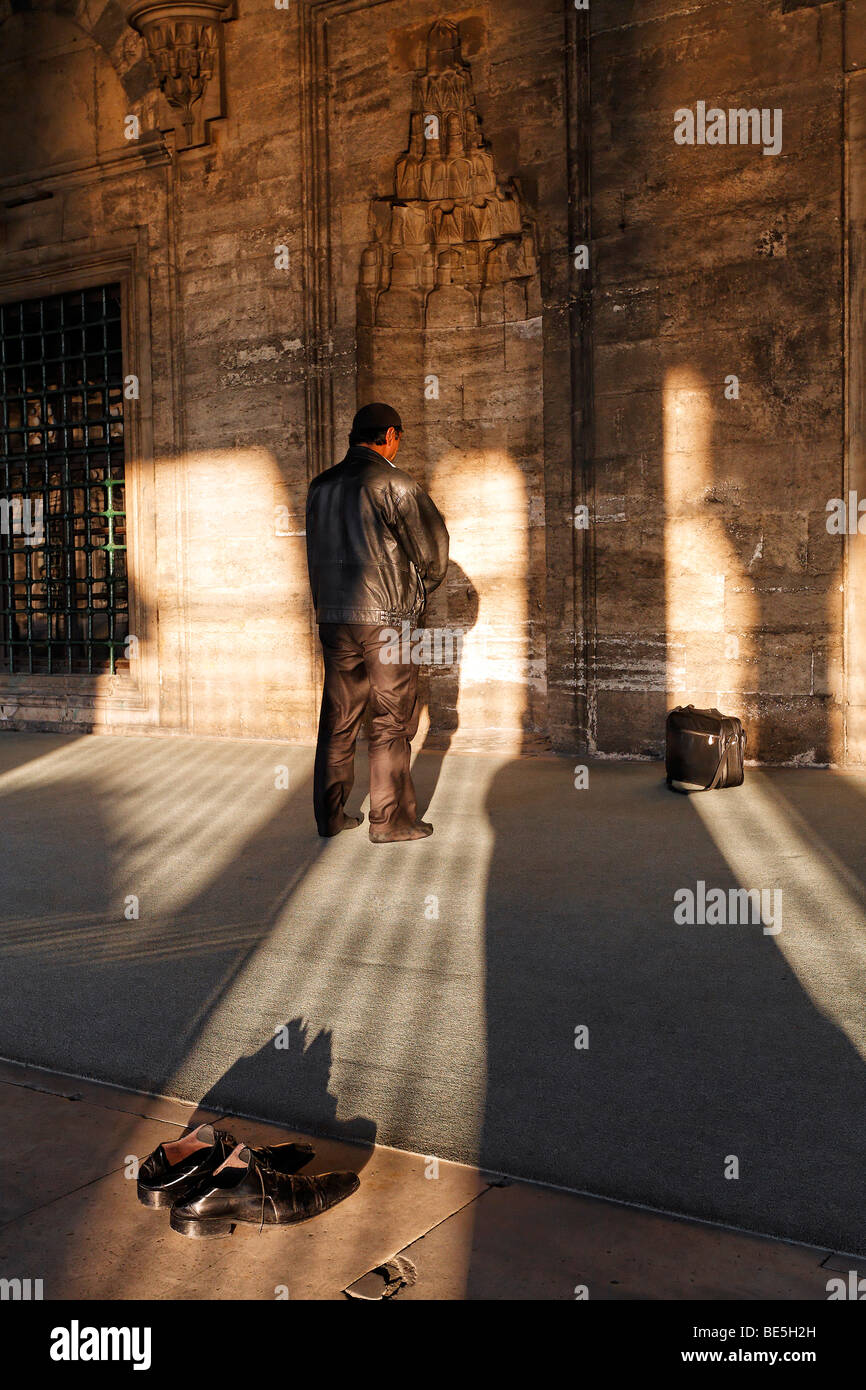 Hombre musulmán orando delante de un nicho de oración, zapatos quitados, Iskele, la Mezquita del Sultán, Ueskuedar Mirimah, Estambul, Turquía Foto de stock