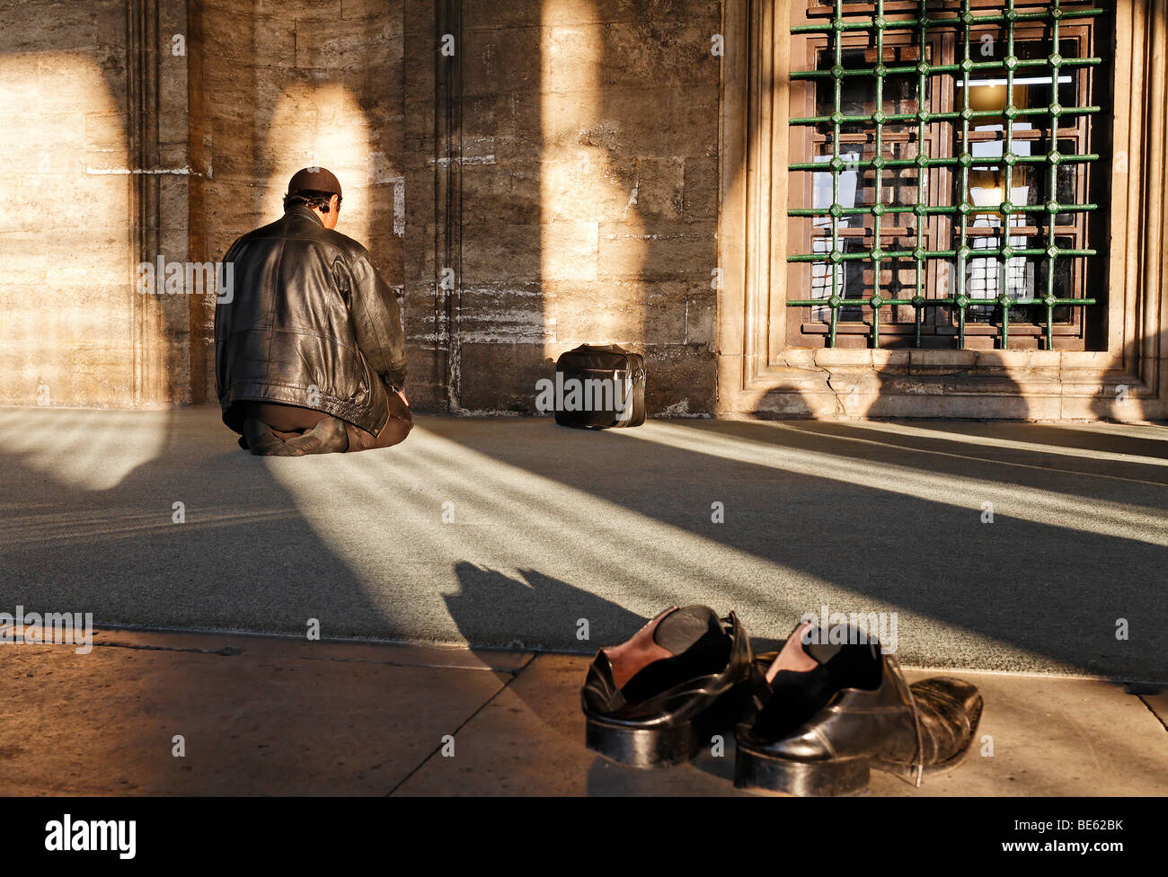 Hombre musulmán orando delante de un nicho de oración, zapatos quitados, Iskele, la Mezquita del Sultán, Ueskuedar Mirimah, Estambul, Turquía Foto de stock
