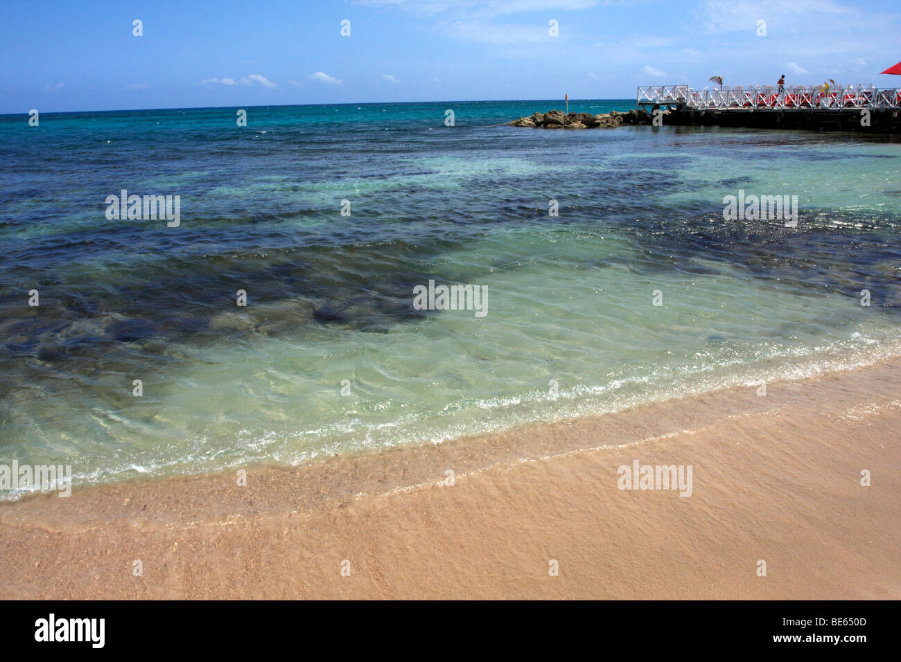 Playa y muelle, playa y a través de las claras aguas del Caribe las algas y rocas. Foto de stock