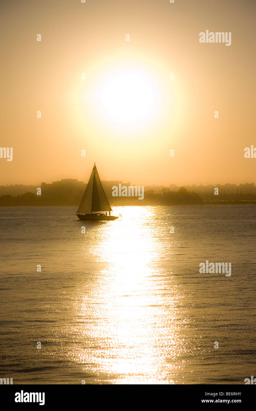 Un velero en el Océano Pacífico con el sol detrás de él en San Diego, California. Foto de stock