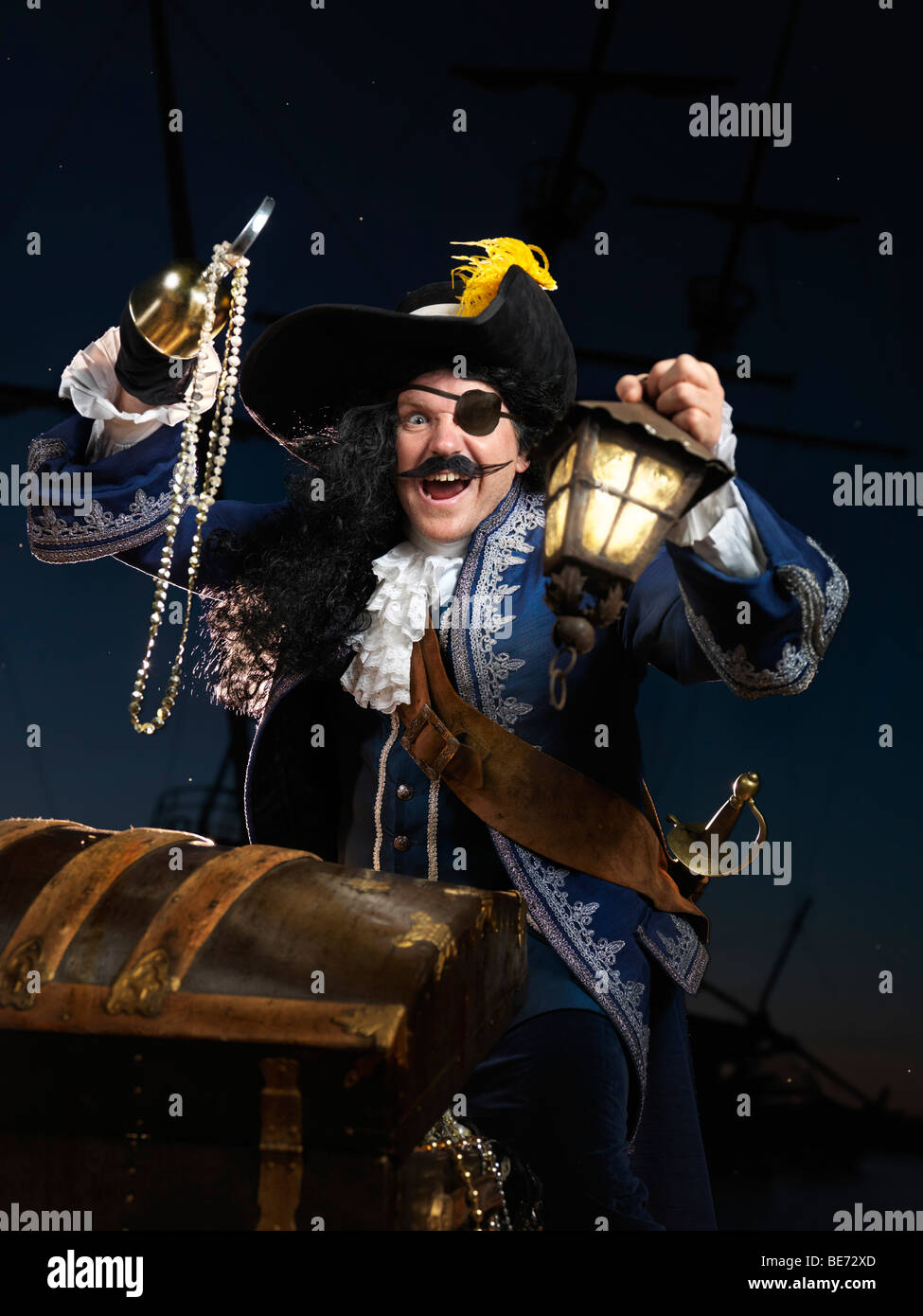 El pirata con una linterna, la apertura de un cofre del tesoro Foto de stock