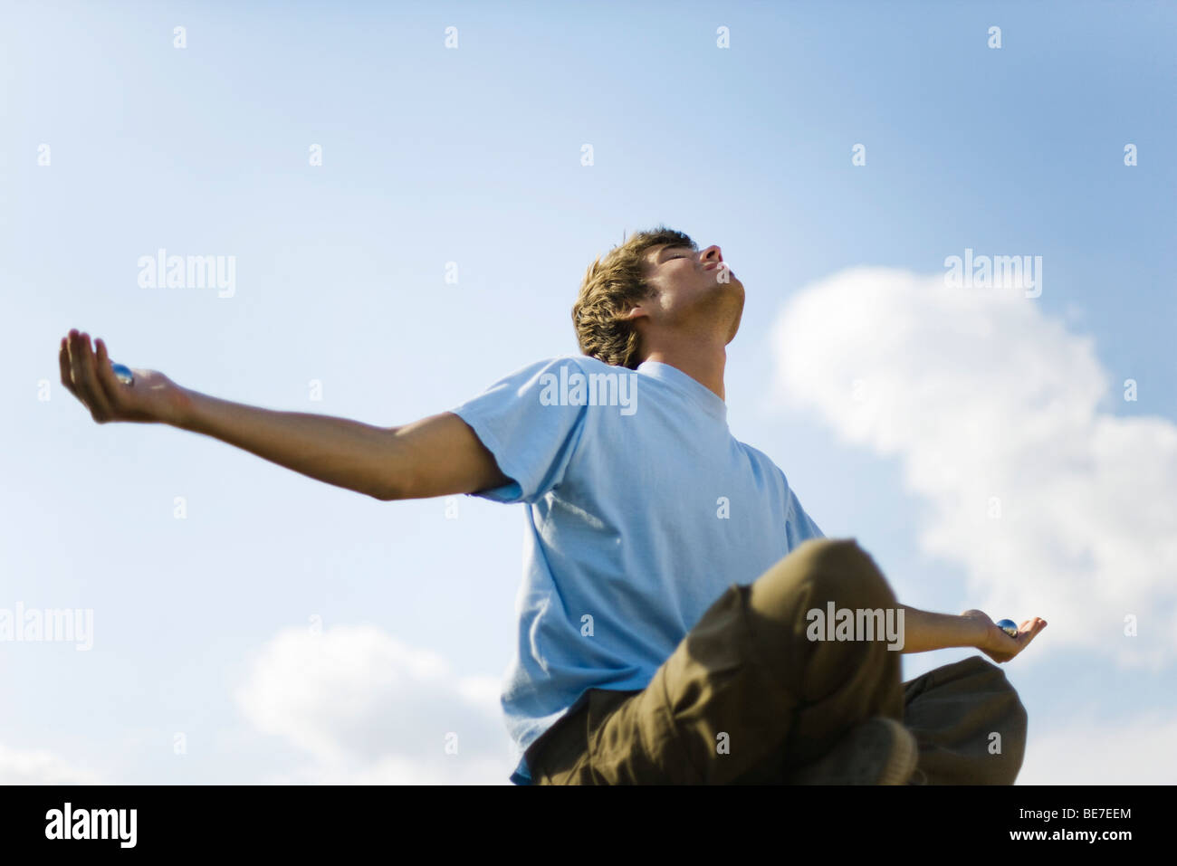 Joven meditando en el exterior, sosteniendo bolas yin yang Foto de stock