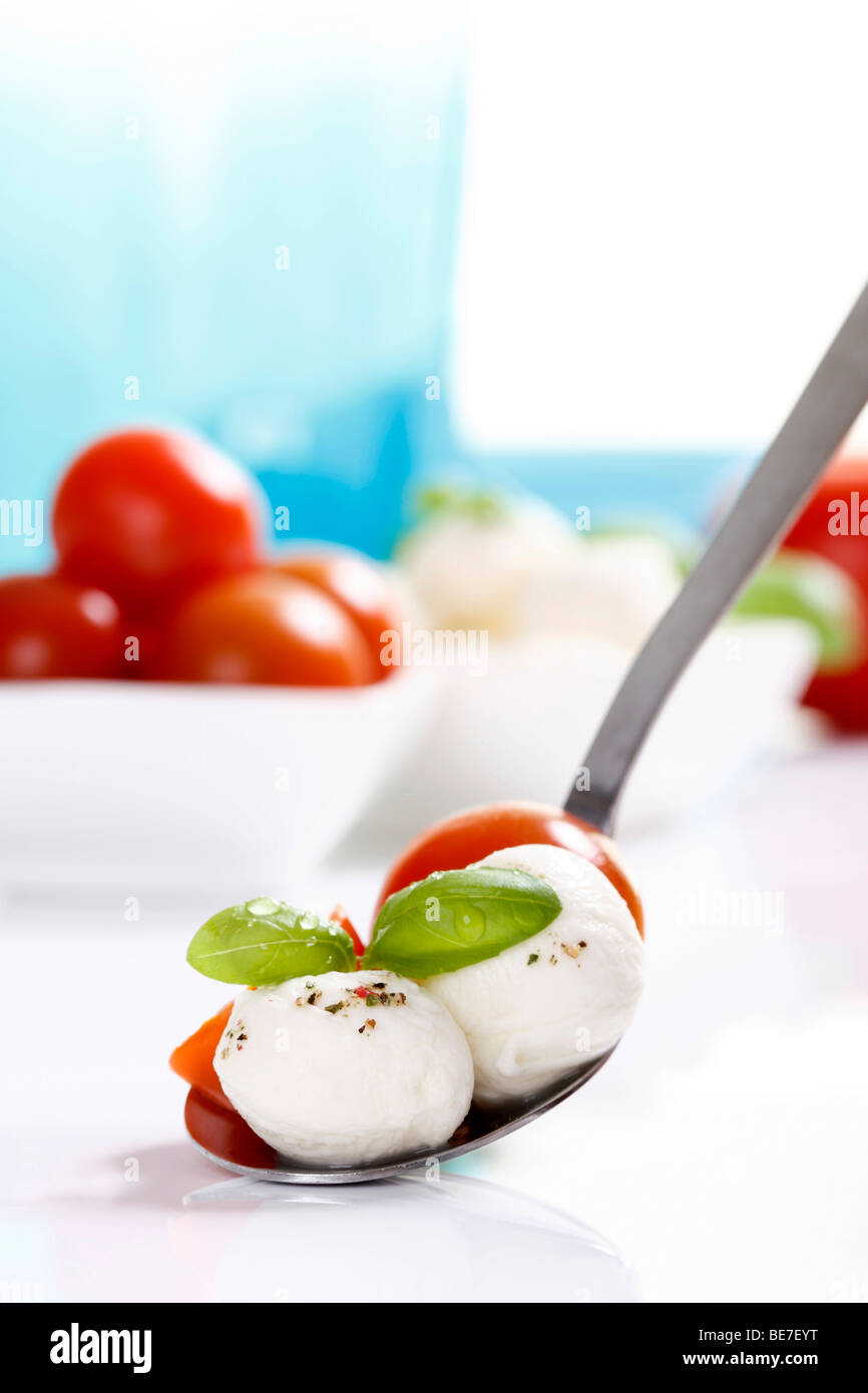 Las bolas de mozzarella con tomates y albahaca en una cuchara Foto de stock