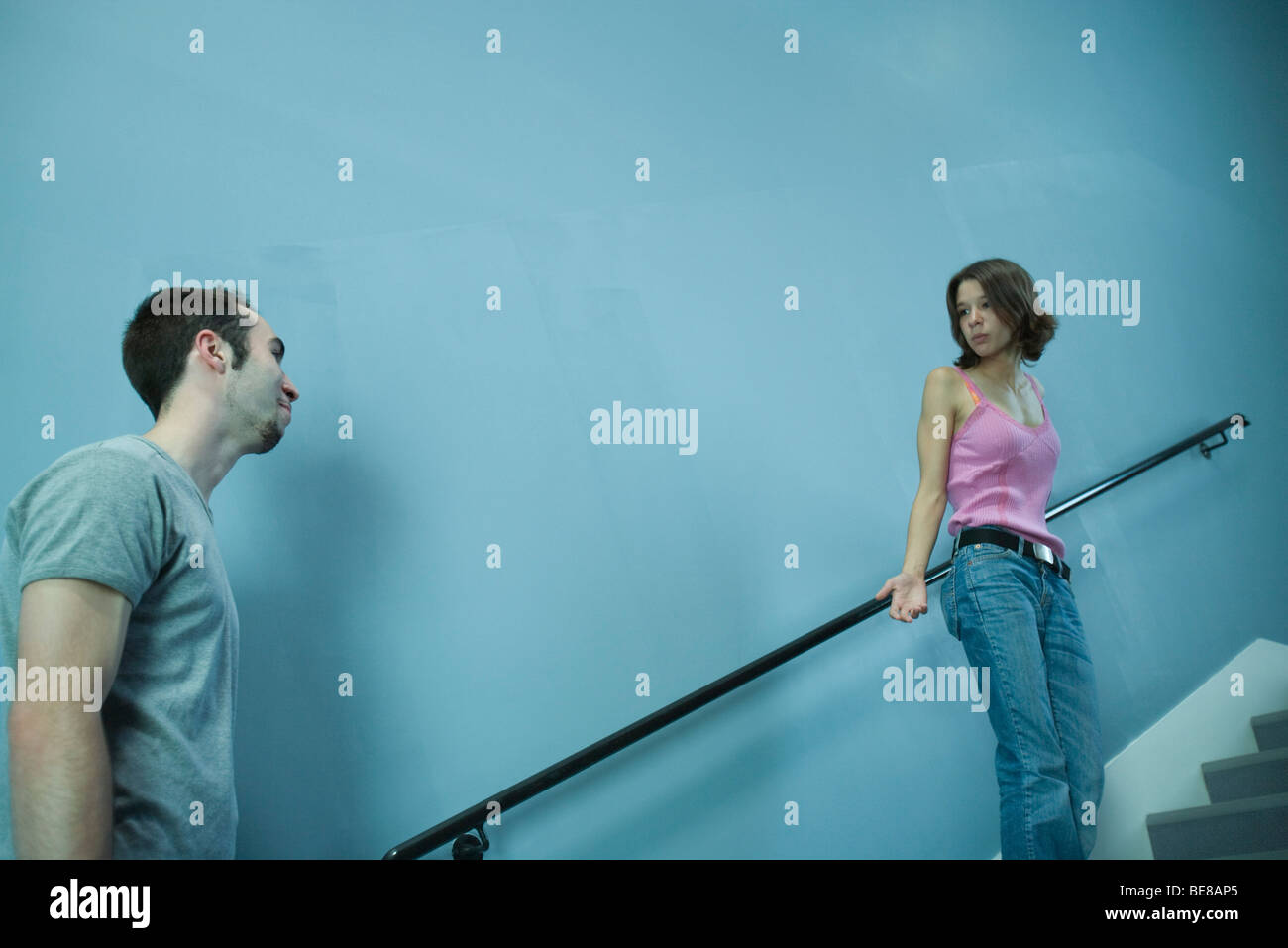 Mujer subir escaleras, buscando questioningly al hombre detrás de ella Foto de stock