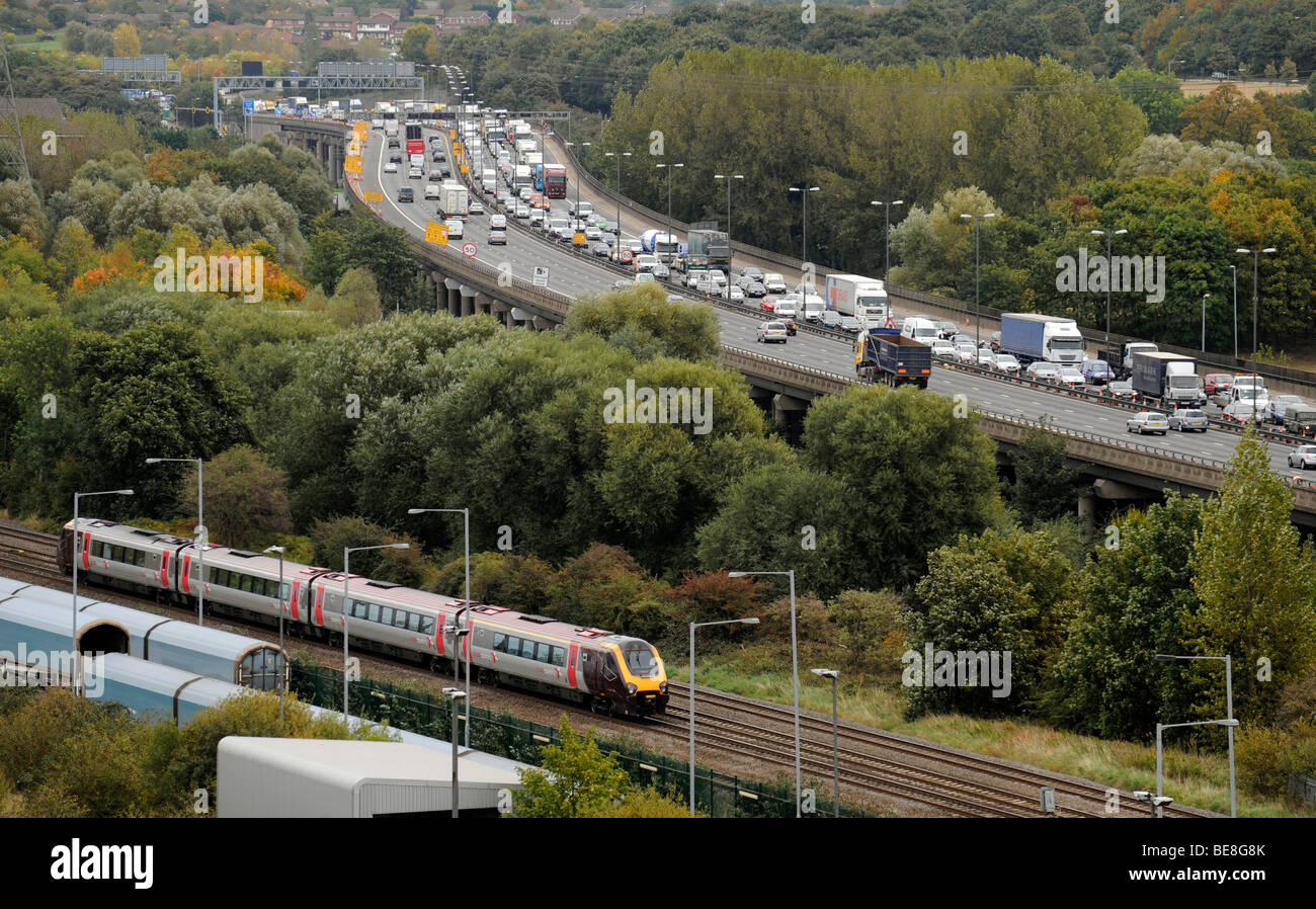 Un tren de cercanías QUE PASA AL LADO DE COLA elevado tráfico en la autopista M6 hacia el norte, cerca de Birmingham, Reino Unido Foto de stock