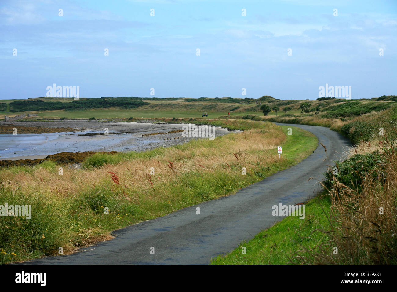 Links golf course situado junto a una bahía arenosa con figuras distantes Foto de stock