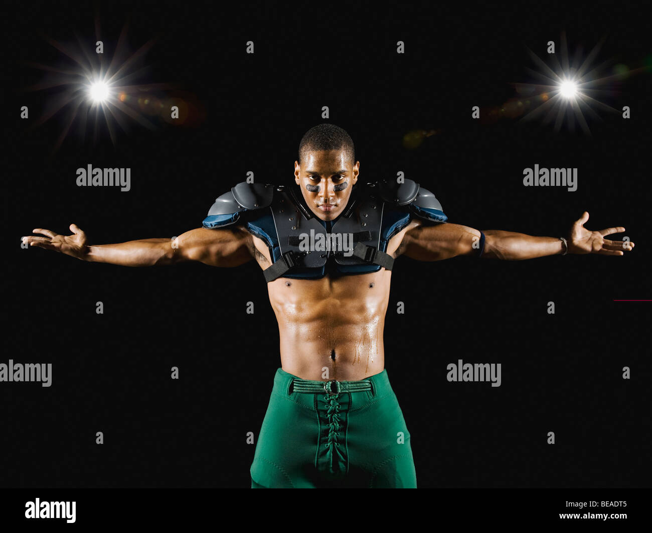 Futbolista africano vistiendo las almohadillas protectoras con los brazos extendidos Foto de stock